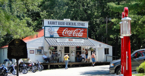 A quaint general store in Rabbit Hash, Kentucky, with people sitting outside and vintage Coca-Cola signage.