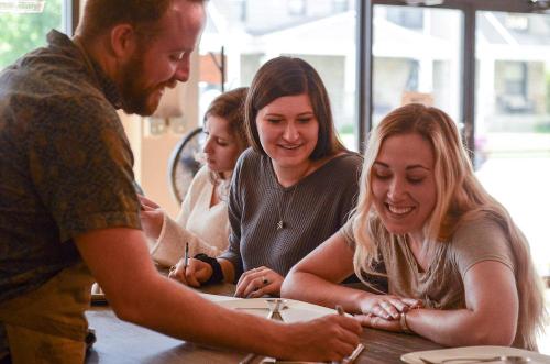 A group of four people engaged in a creative activity, smiling and interacting at a table in a bright, inviting space.