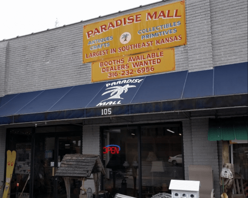Exterior of Paradise Mall, featuring a sign for antiques and collectibles, with an "Open" neon sign in the window.