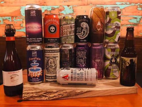 A variety of colorful beer cans arranged on a wooden board against a rustic background.