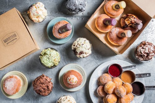 An assortment of colorful desserts, including donuts, ice cream, and toppings, arranged on a metallic surface.