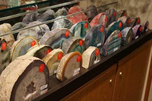 A display of colorful agate slices in various shapes, labeled with price tags, arranged in a glass case.