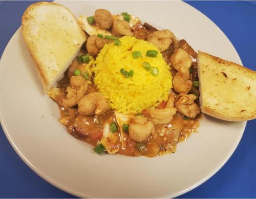 A plate of yellow rice topped with shrimp, served with two slices of toasted bread on the side.