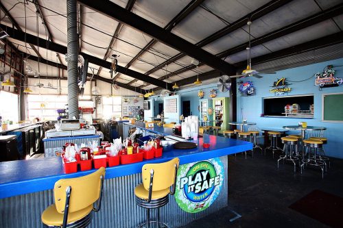 Interior of a casual diner with a blue bar, yellow stools, and colorful decor, featuring a relaxed, inviting atmosphere.