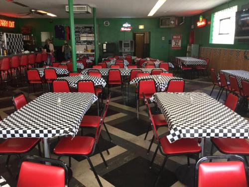 A diner interior with red chairs and checkered tablecloths, featuring empty tables and a retro vibe.