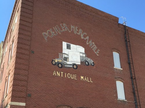 Mural on a brick building featuring a vintage truck and the text "Poshler Mercantile Antique Mall."