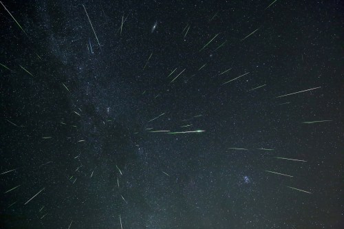 A starry night sky filled with streaks of light from meteors, creating a dynamic and vibrant celestial scene.