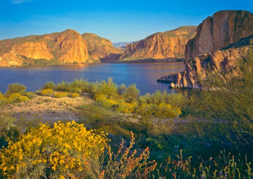A serene landscape featuring mountains and a calm body of water, with soft, muted colors and a hazy atmosphere.
