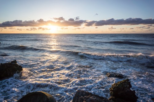 A serene ocean scene at sunset, with gentle waves and a colorful sky reflecting the fading light.