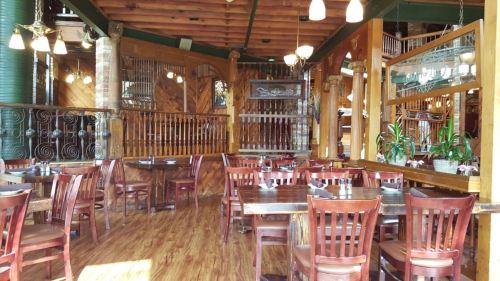 Cozy restaurant interior with wooden tables, chairs, and rustic decor, featuring warm lighting and a welcoming atmosphere.