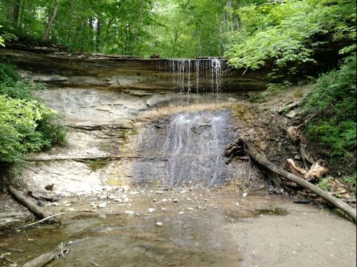 A serene waterfall cascading over rocky terrain, surrounded by lush green trees and foliage.