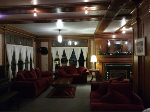 Cozy living room with red sofas, wooden paneling, a fireplace, and soft lighting.