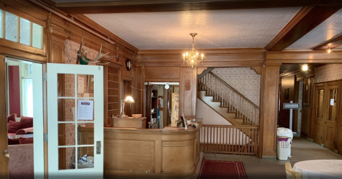 A wooden reception area with a staircase, vintage decor, and a welcoming atmosphere.