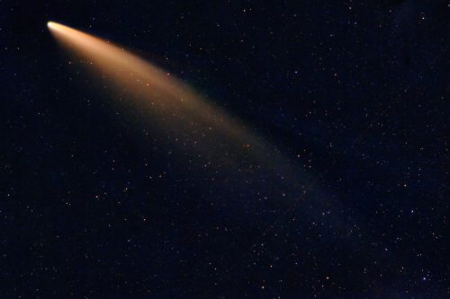 A bright comet with a long, glowing tail against a dark starry sky.