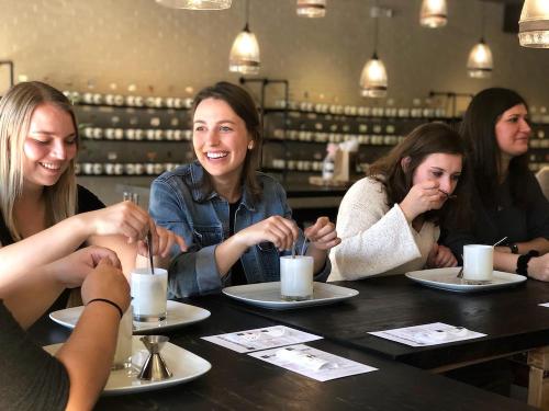 A group of five women sitting at a table, enjoying drinks and engaging in conversation at a stylish café.