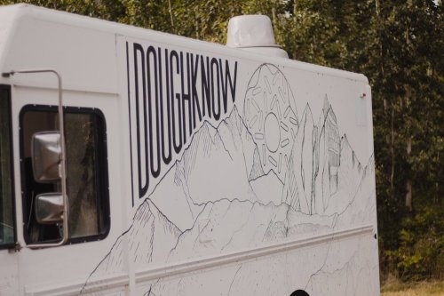 A food truck with a mountain landscape design and the name "DOUGHKNOW" prominently displayed on the side.