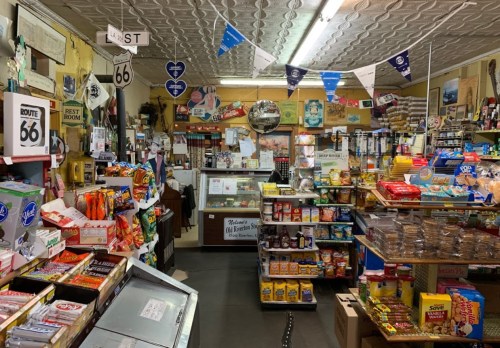 A vintage convenience store filled with snacks, drinks, and Route 66 memorabilia, featuring a cozy, nostalgic atmosphere.