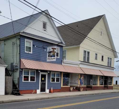 A blue and yellow building with striped awnings, featuring a sign for "Mom's" and an open flag.