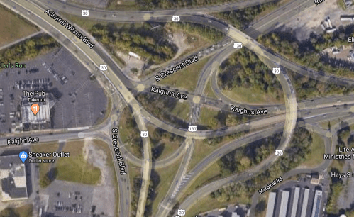 Aerial view of a highway interchange with multiple roads and nearby commercial areas.