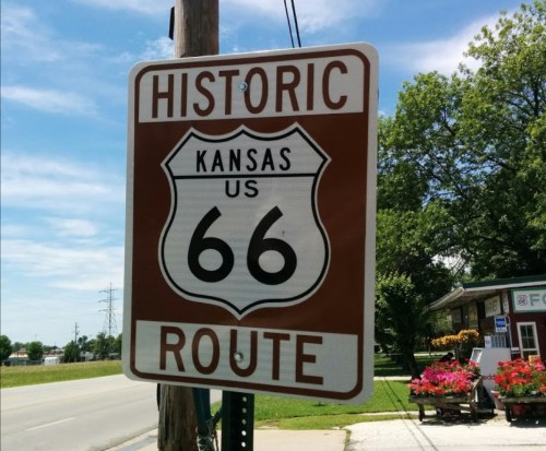 Sign for Historic Route 66 in Kansas, featuring a brown and white design against a blue sky.