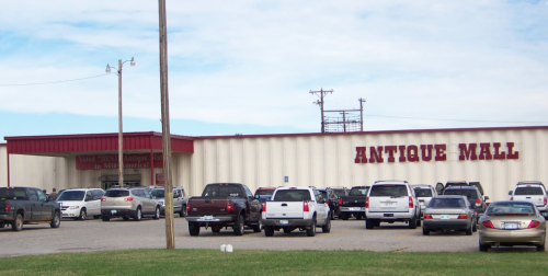 Exterior of an Antique Mall with a parking lot filled with cars under a clear blue sky.