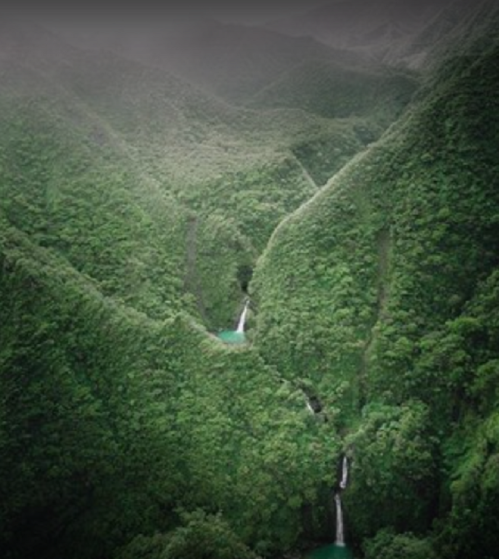 Lush green mountains with deep valleys and small waterfalls cascading into turquoise pools.