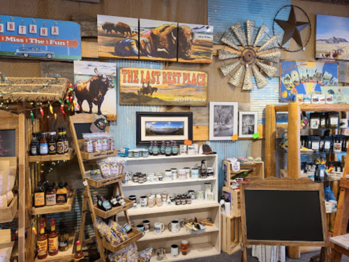 A cozy shop interior featuring rustic decor, shelves of local products, and Montana-themed artwork on the walls.