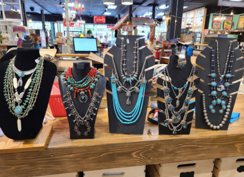 A display of colorful necklaces on black stands in a vibrant store setting.