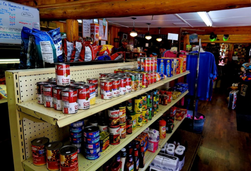 A store shelf filled with various canned goods and snacks, including Campbell's soup and other packaged items.