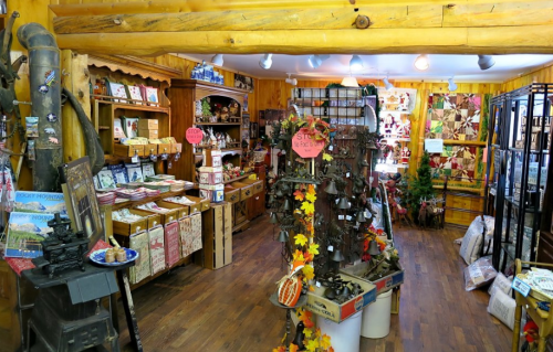 A cozy gift shop filled with wooden decor, crafts, and seasonal items, featuring warm wooden walls and a rustic atmosphere.