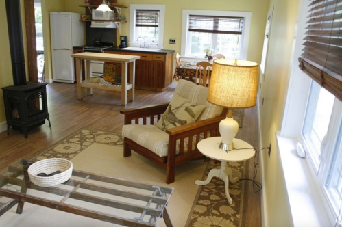 Cozy living space featuring a wooden chair, lamp, and kitchen area with a dining table and appliances.