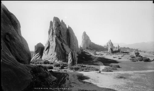 Black and white landscape featuring towering rock formations and a winding path in a rugged terrain.