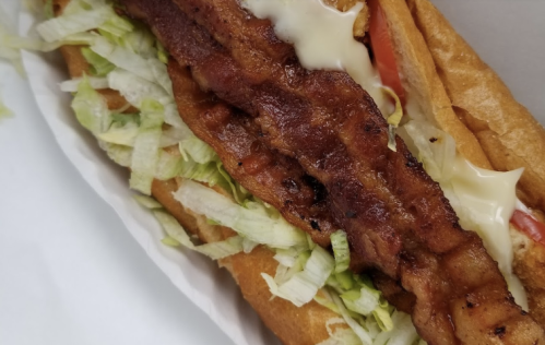 A close-up of a sandwich with crispy bacon, lettuce, tomato, and mayonnaise in a toasted bun.