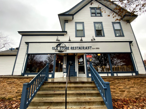 Front view of the Ole Store Restaurant, a historic building with stairs leading up to the entrance, established in 1869.
