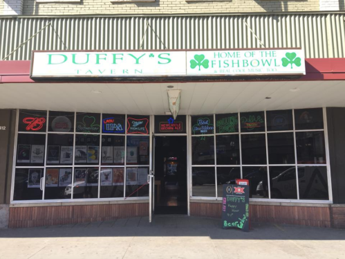 Exterior of Duffy's Tavern, featuring a sign that reads "Home of the Fishbowl" and various neon beer advertisements.