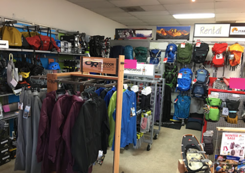 A retail store displaying various outdoor gear, including backpacks, jackets, and equipment for rent.