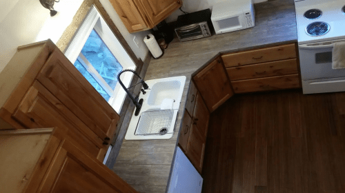 Aerial view of a modern kitchen featuring wooden cabinets, a sink, and appliances like a microwave and stove.