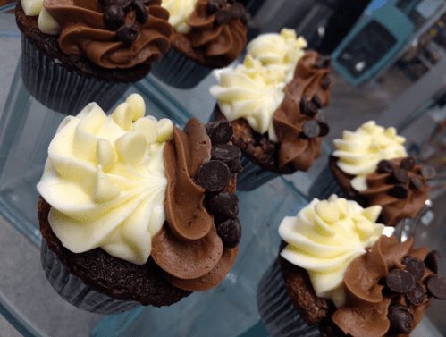 A display of chocolate and vanilla cupcakes topped with swirls of frosting and chocolate chips.