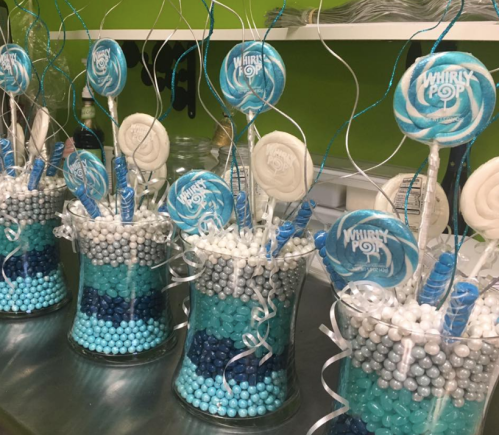Colorful candy display in glass vases, featuring blue and white candies, lollipops, and decorative swirls.