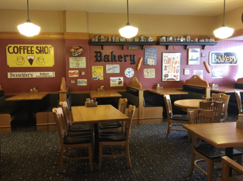 Cozy bakery interior with wooden tables, booths, and vintage signs on the walls, creating a warm atmosphere.