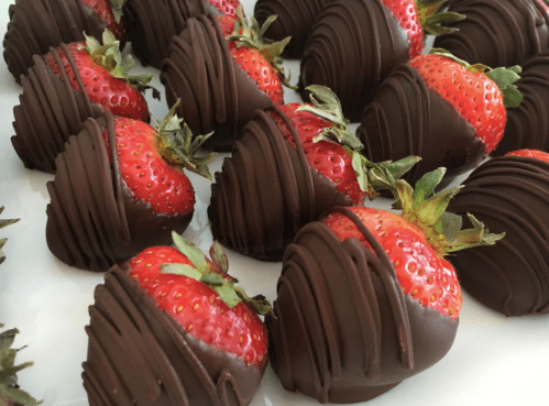 A close-up of chocolate-covered strawberries arranged neatly on a white plate.