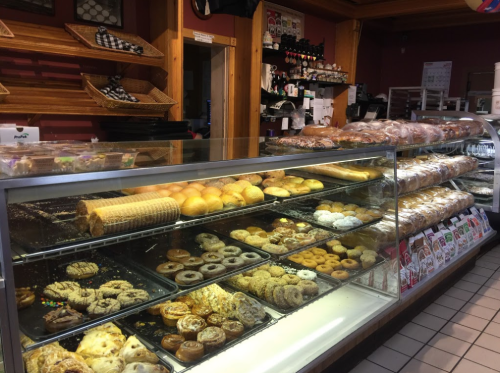 A bakery display case filled with various pastries, donuts, and bread, showcasing a variety of baked goods.