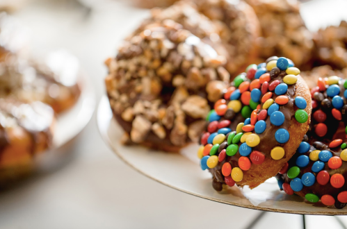 A close-up of colorful donuts topped with chocolate and candy-coated chocolates, displayed on a plate.