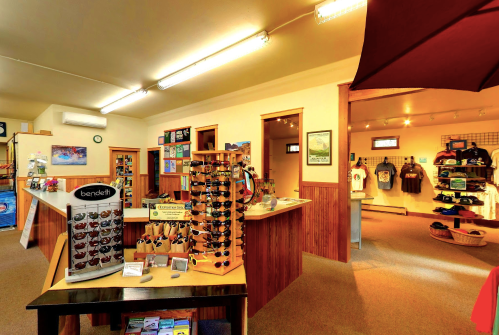 Interior of a retail store featuring sunglasses displays, clothing racks, and various outdoor merchandise.