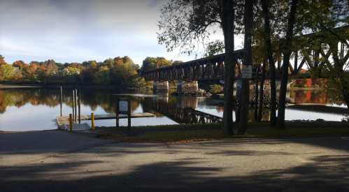 A tranquil river scene with a bridge, surrounded by autumn foliage and reflections on the water.
