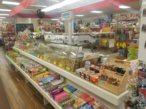 A colorful candy store display with various sweets, snacks, and treats arranged on shelves and counters.