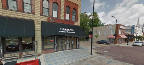 Exterior view of Nabila's Garden Restaurant, featuring a black awning and brick buildings on a street corner.