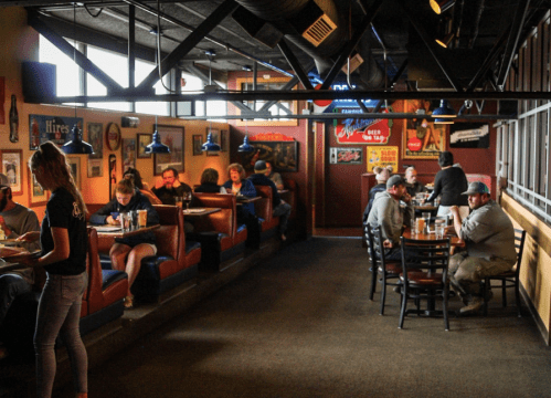 A cozy restaurant interior with booths and tables, patrons enjoying meals, and colorful decor on the walls.