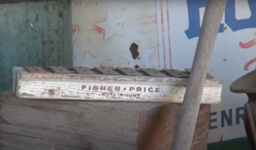 A vintage Fisher-Price toy xylophone resting on wooden planks in a rustic setting.