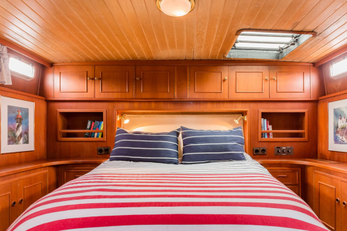 Cozy bedroom with a striped bedspread, wooden cabinetry, and nautical-themed artwork on the walls.